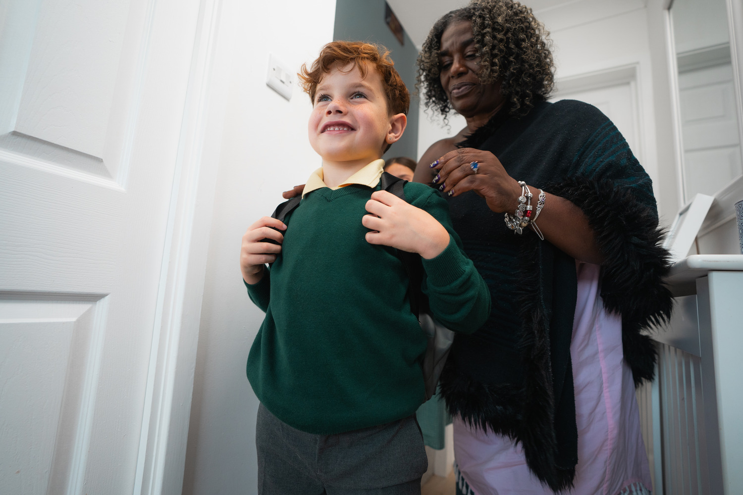 Mum putting on son's school backpack