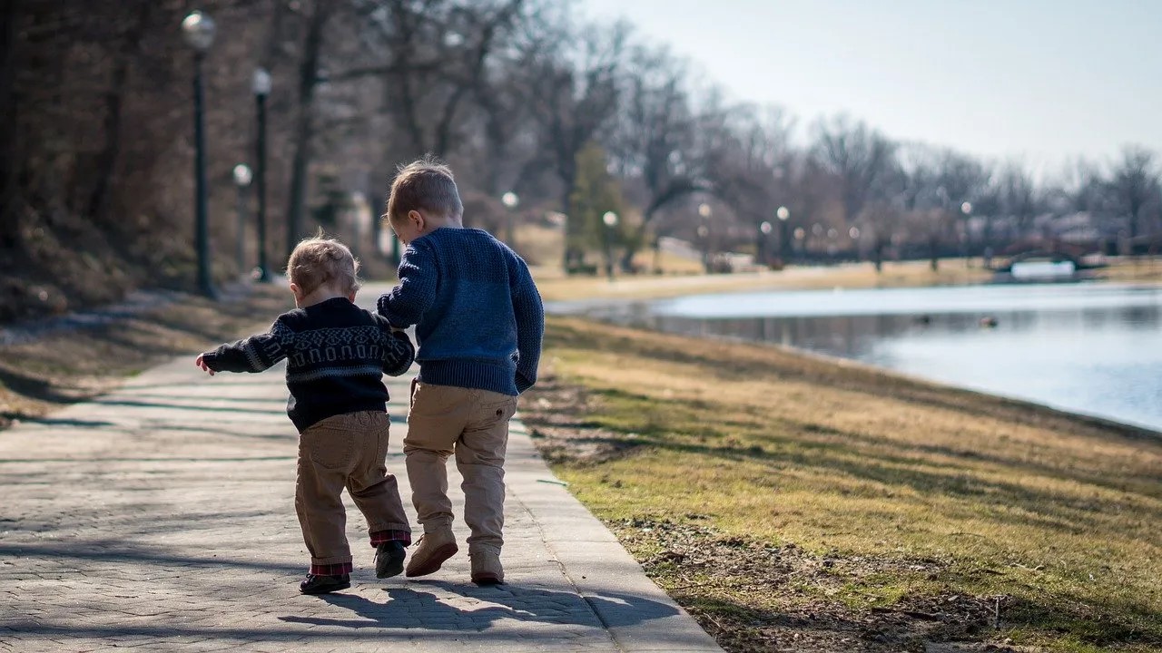 Two boys walking along a path alongside a river